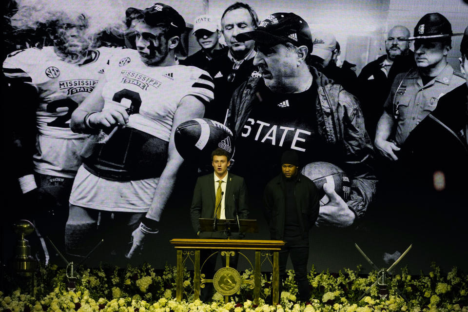 Mississippi State quarterback Will Rogers, left, reflects on impact on his life by the late Mississippi State head football coach Mike Leach, while linebacker Nathaniel Watson, waits to speak during Leach's memorial service in Starkville, Miss., Tuesday, Dec. 20, 2022. A montage of black-and-white photographs of Leach's tenure with the players was shown on the video boards during their comments. Leach died, Dec. 12, 2022, from complications related to a heart condition at 61. He was in his third year as head coach. (AP Photo/Rogelio V. Solis)