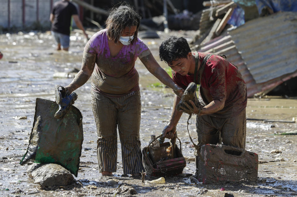 Residents carry belongings from their homes at the typhoon-damaged Kasiglahan village in Rodriguez, Rizal province, Philippines, Friday, Nov. 13, 2020. Thick mud and debris coated many villages around the Philippine capital Friday after Typhoon Vamco caused extensive flooding that sent residents fleeing to their roofs and killing dozens of people. (AP Photo/Aaron Favila)