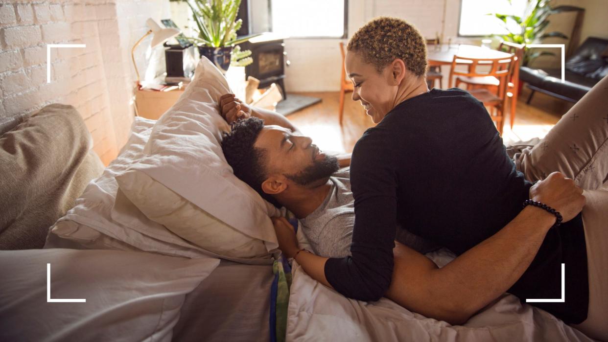  Couple lying romantic in bed looking into each other's eyes, representing yoga sex positions. 