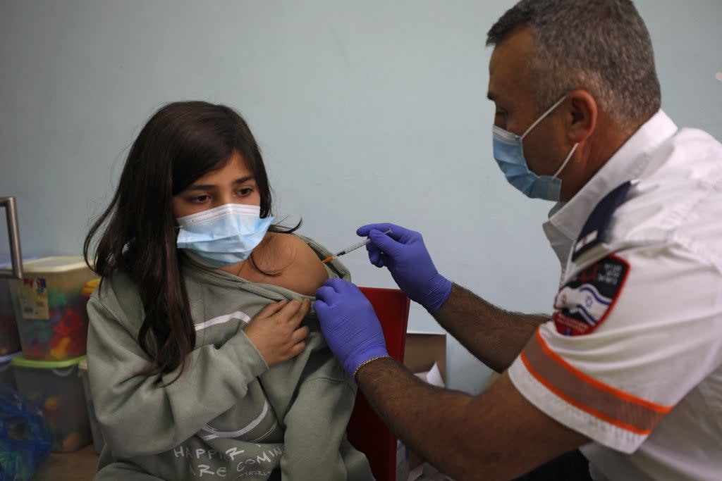 An Israeli health worker administers a dose of the Pfizer/BioNTech Covid-19 vaccine to a student (AFP via Getty Images)