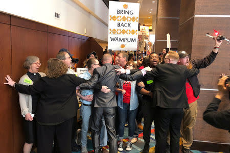 Guards hold back about 100 protestors gathered in a hotel lobby outside Wells Fargo & Co’s annual shareholder meeting in Des Moines, Iowa, U.S., April 24, 2018. REUTERS/Ross Kerber