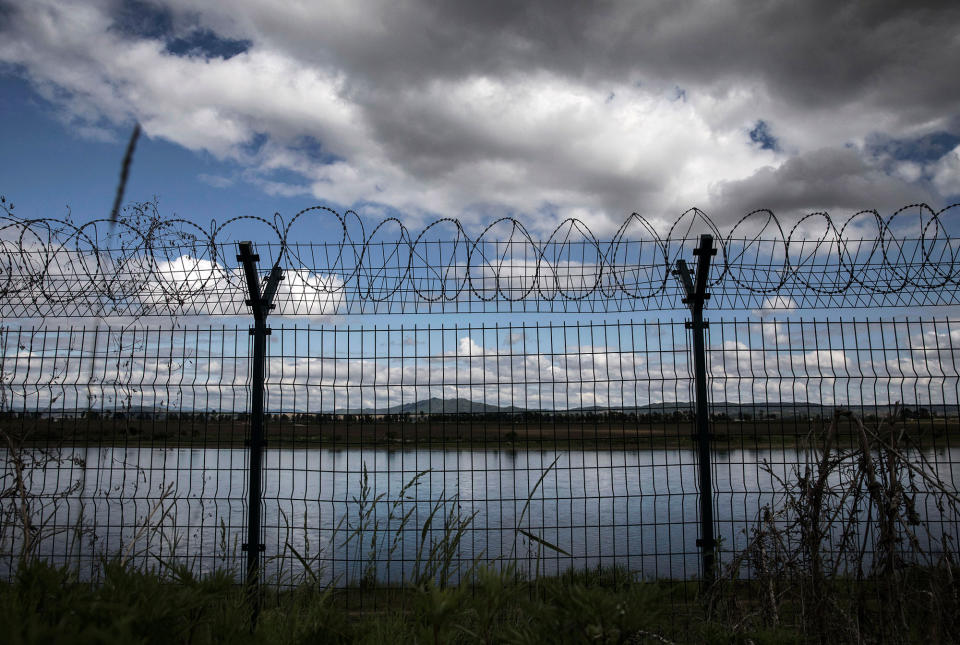 A razor-wired fence protects the border