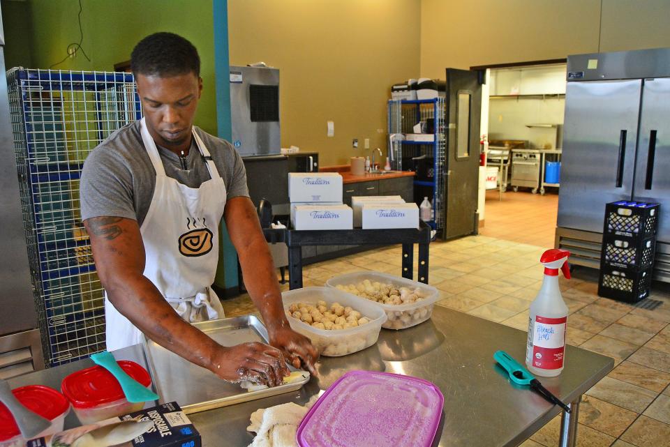 The Biscuit Center owner Scott Pass on Wednesday butters up a pan on which to bake what he calls BBs, or Biscuit Bites, at the temporary home of the Como Cooks Kitchens on Walnut Street. It's a new product that is not yet released publicly.