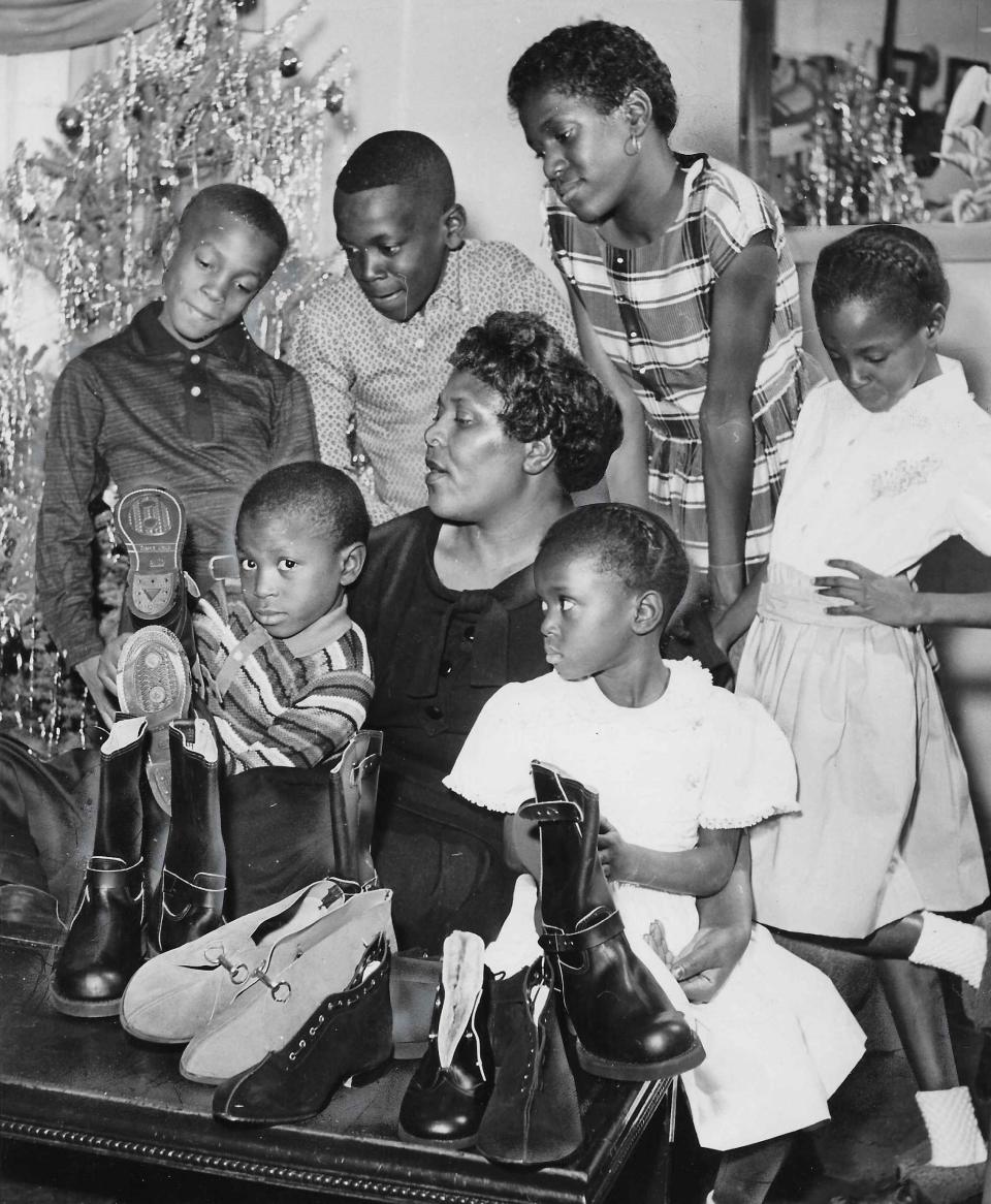 Helen Arnold and six of her children look over some of the Christmas gifts purchased with a $350 gift from an unknown benefactor in 1959. Clockwise from left, the children are Gerald, 6, Gary, 9, John, 11, Gale, 12, Carla, 7, and Donna, 4.