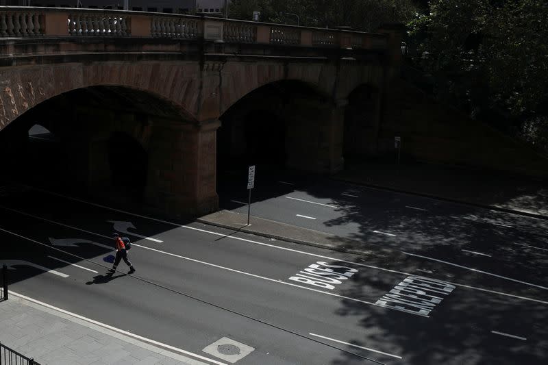 A man crosses an almost empty street during a workday following the implementation of stricter social-distancing and self-isolation rules to limit the spread of the coronavirus disease (COVID-19) in Sydney