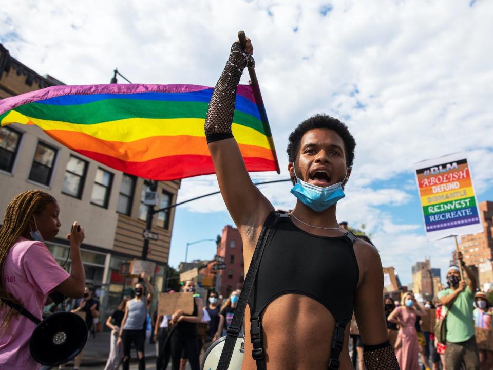 A demonstrator in New York carrying a rainbow flag and marching in support of the Black Lives Matter movement and equal rights for LGBTQ people.