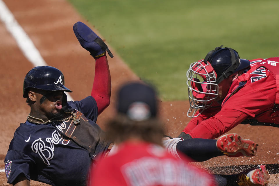 Atlanta Braves' Ronald Acuna Jr., (13) safely slides into home plate against Boston Red Sox catcher Jett Bandy in the first inning during a spring training baseball game on Monday, March 1, 2021, in Fort Myers, Fla. (AP Photo/Brynn Anderson)