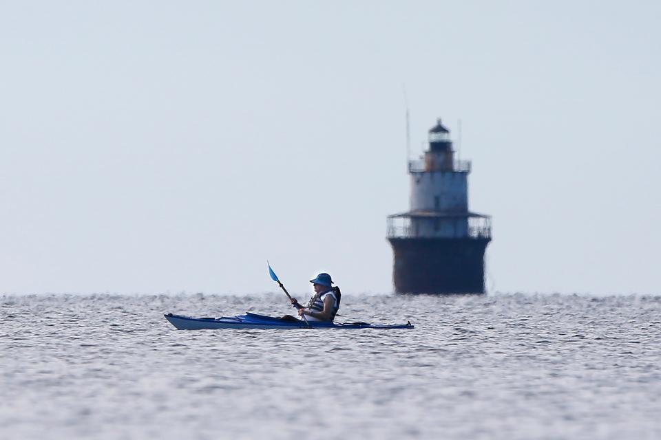A kayaker makes his way across Buzzards Bay past the Butler Flats lighthouse as seen from Fort Phoenix in Fairhaven.