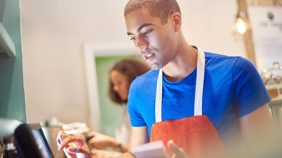 coffee shop worker entering the order into a digital display screen.