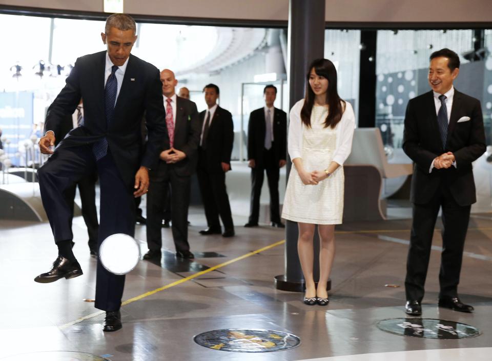 U.S. President Barack Obama stops a soccer ball kicked by "Asimo" the robot while visiting Miraikan in Tokyo