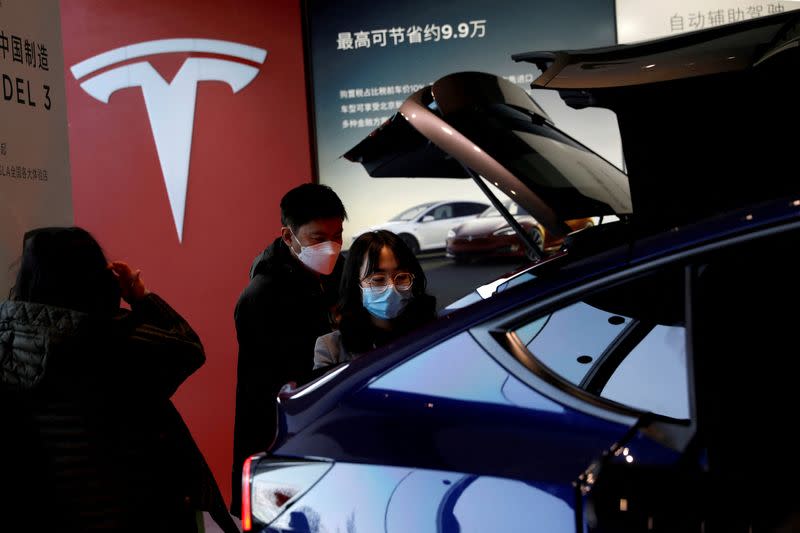 FILE PHOTO: FILE PHOTO: Visitors wearing face masks check a China-made Tesla Model Y sport utility vehicle (SUV) at the electric vehicle maker's showroom in Beijing