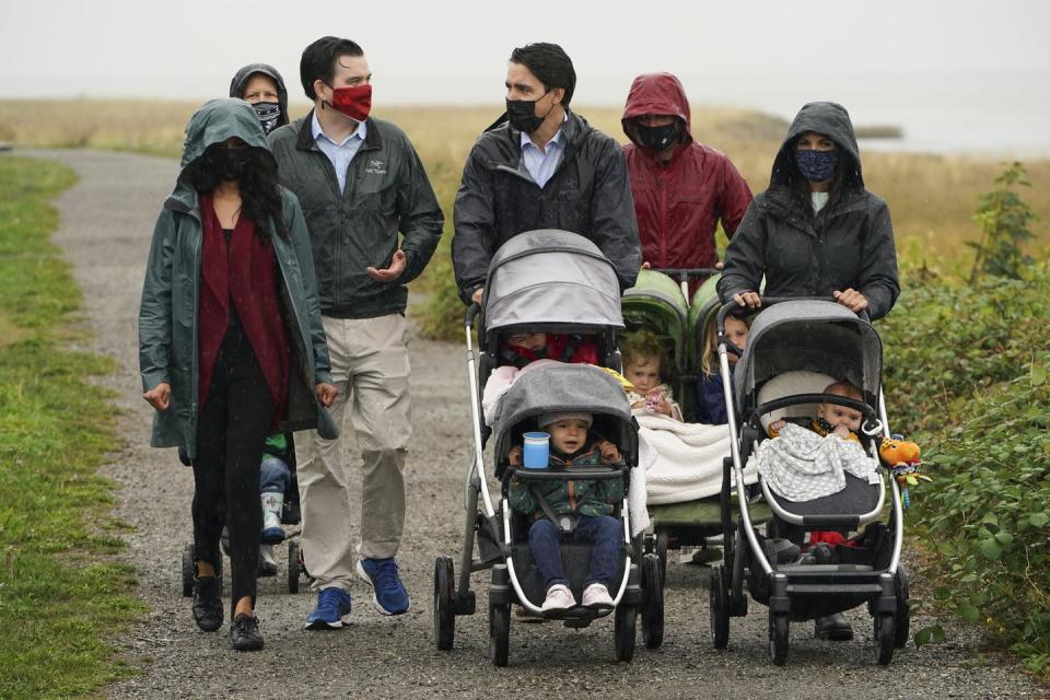 Trudeau pushes a stroller as he walks with families, including two women pushing strollers.