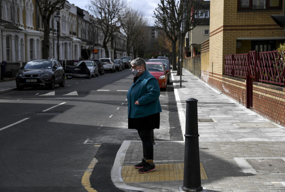 The Rev. April Keech, an Anglican priest, who organizes food deliveries to old and vulnerable people, stands on a street corner in London, Saturday, March 28, 2020. Keech and her team of volunteers have spent the past two weeks buying groceries, filling prescriptions and making deliveries to residents in east London who are at risk of serious illness or death from the COVID-19 disease. (AP Photo/Alberto Pezzali)