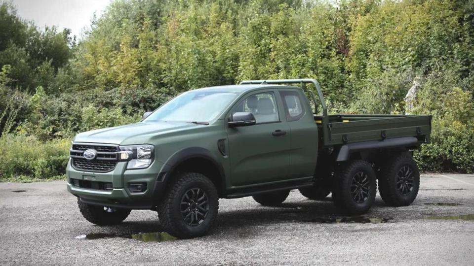 a dark green ford ranger pickup with a 6x6 layout sits on a gravel road in front of some shrubs