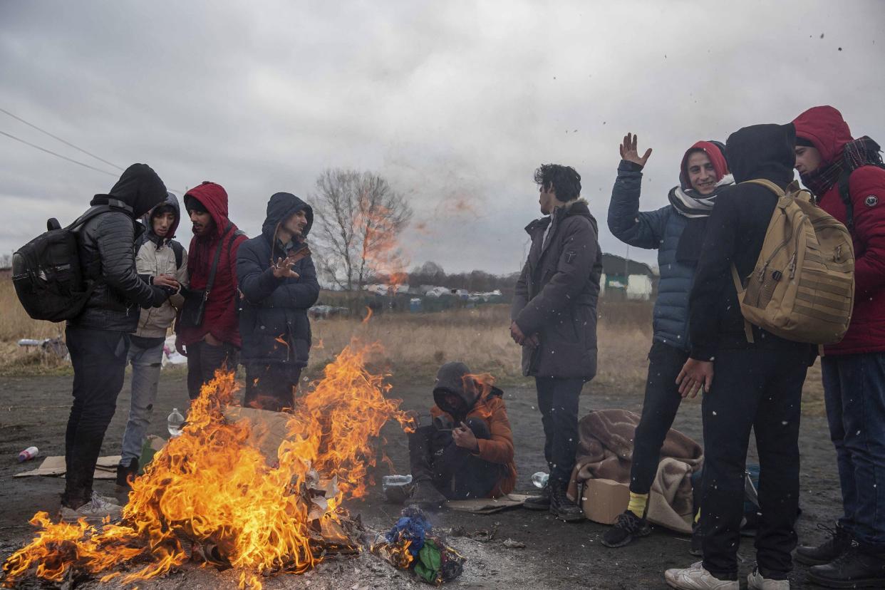 Refugees fleeing conflict in Ukraine warm up near a fire after arriving at the Medyka border crossing in Poland on Monday, Feb. 28, 2022. The head of the United Nations refugee agency says more than a half a million people had fled Ukraine since Russia’s invasion on Thursday.