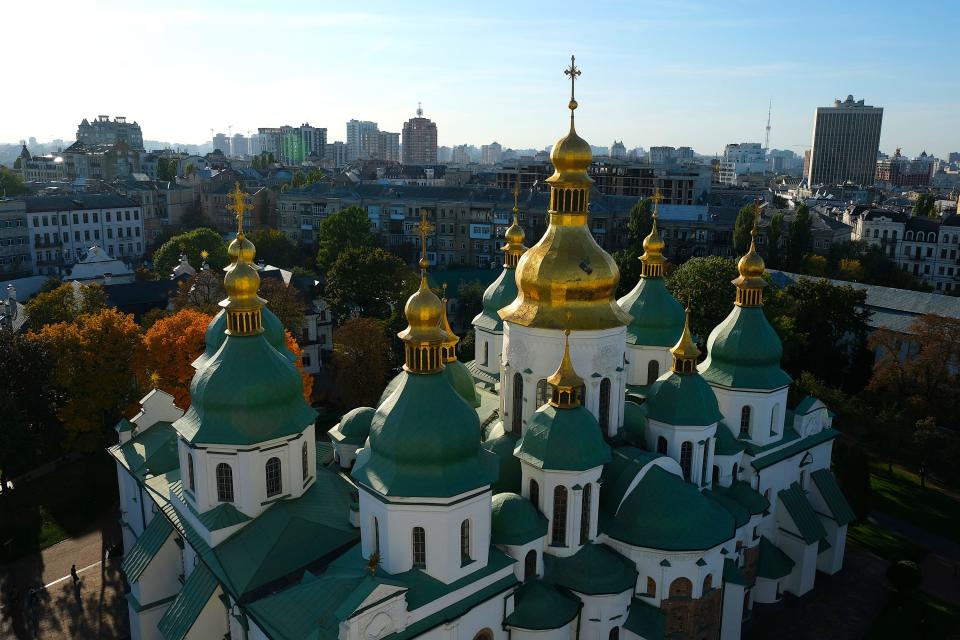 cathedral with gold top shines on a sunny day with the kyiv city skyline in the background