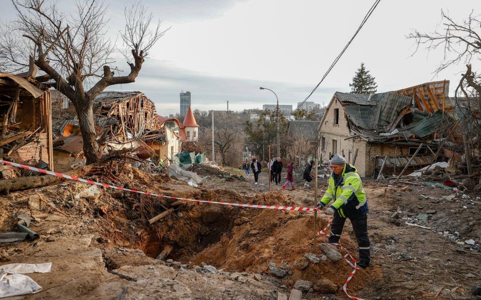 A man sets up safety tape around a crater in the Solomyansk district of Kyiv - Anadolu