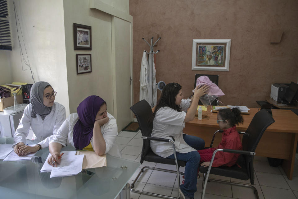 In this Wednesday, July 24, 2019 photo, a nurse takes off a protective mask as she performs skin check-ups on 6 year-old Yasmin, who is affected by a rare disorder called xeroderma pigmentosum, or XP, inside a hospital in Casablanca, Morocco. (AP Photo/Mosa'ab Elshamy)