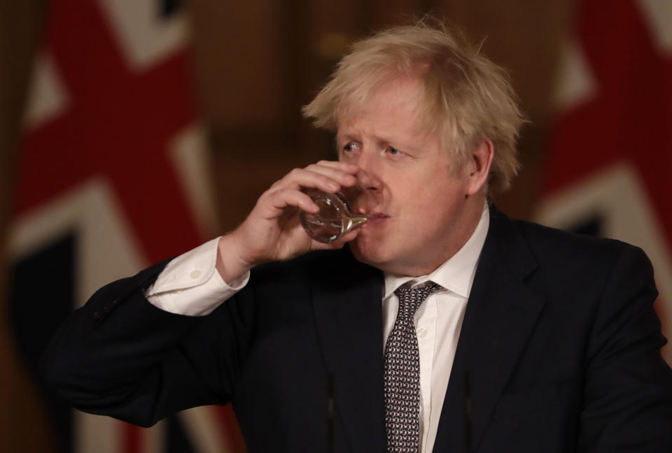 Britain's Prime Minister Boris Johnson takes a drink as he listens to a question from the media during a news conference on the ongoing situation with the coronavirus pandemic, inside 10 Downing Street in London, Wednesday, Dec. 16, 2020. (AP Photo/Matt Dunham, Pool)