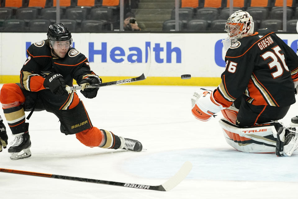 Anaheim Ducks defenseman Ben Hutton, left, and goaltender John Gibson try to stop a shot during the first period of an NHL hockey game against the Los Angeles Kings Monday, March 8, 2021, in Anaheim, Calif. (AP Photo/Mark J. Terrill)