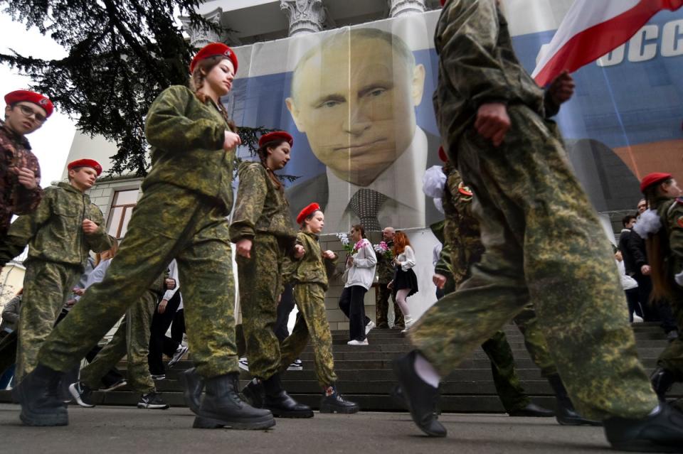 Youths parade to mark the ninth anniversary of the Crimea annexation with a banner reading: “Russia doesn’t start wars, it ends them” ahead of Putin’s visit, in Yalta, Crimea (AP)