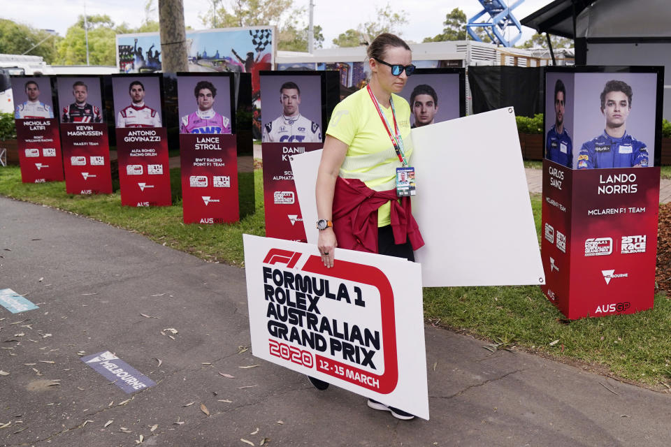 A woman takes away signs after the cancellation of the Australian Formula One Grand Prix in Melbourne, Friday, March 13, 2020. The first F1 Grand Prix of the season was canceled two hours before the first official practice was set to start Friday after organizers relented to pressure to call it off amid the spreading coronavirus. (Michael Dodge/AAP Image via AP)