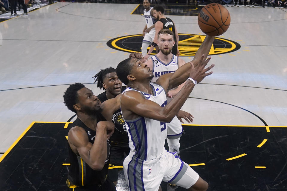 Sacramento Kings guard De'Aaron Fox, foreground, shoots against Golden State Warriors forward Andrew Wiggins, left, and forward Kevon Looney during the second half of Game 3 of an NBA basketball first-round playoff series in San Francisco, Thursday, April 20, 2023. (AP Photo/Jeff Chiu)