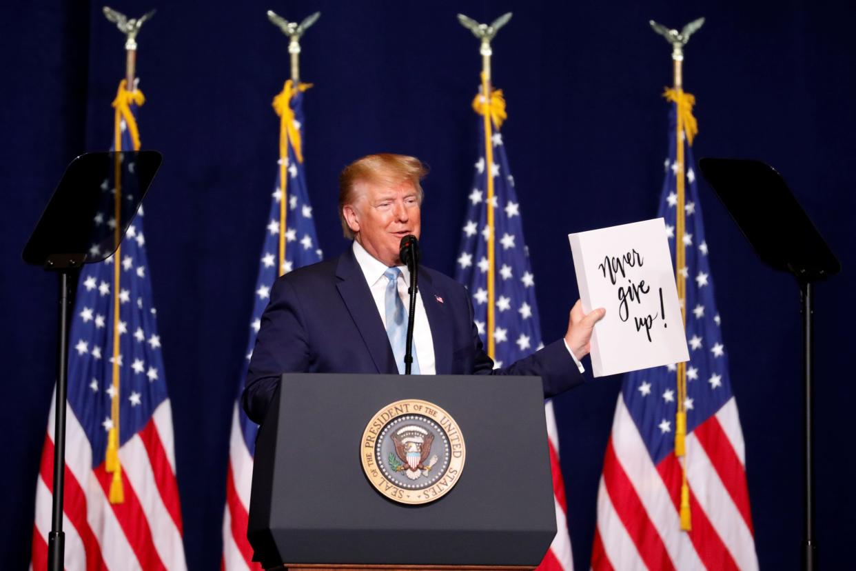 Trump holds a sign that reads, "Never give up!" as he speaks to evangelical supporters in Miami on Jan. 3, 2020. (Photo: Eva Marie Uzcategui/Reuters)