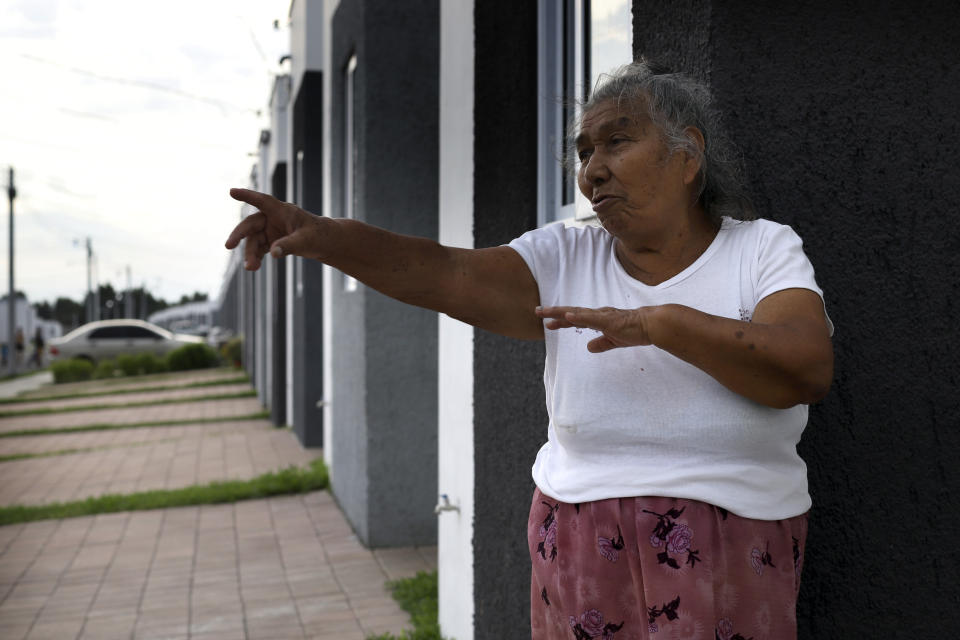 Victoria Crisostoma, a survivor of the October 2002 landslide that devastated her community Los Angelitos, speaks during an interview from the doorstep of her new government donated home, in the private residential development Ciudad Marsella, El Salvador, Tuesday, July 27, 2021. The 73-year-old grandmother said, "We are not allowed to cook with wood and we have to pay for gas. I cannot afford it. We are not allowed to grind corn so I cannot make my own tortillas and I have to buy them. I have no income." (AP Photo/Salvador Melendez)