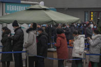 People wearing face masks to help protect from the coronavirus line up to get a swab for the COVID-19 test at a hospital in Beijing, Sunday, Jan. 23, 2022. Chinese authorities have called on the public to stay where they are during the Lunar New Year instead of traveling to their hometowns for the year's most important family holiday. (AP Photo/Andy Wong)