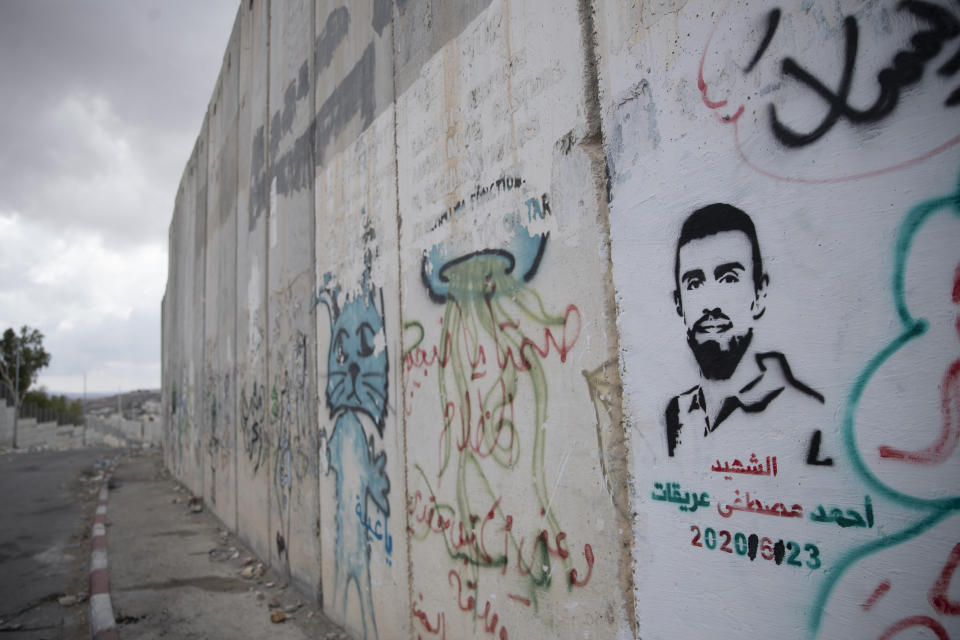 A graffiti that depicts Ahmed Erekat, who was shot dead by Israeli forces at a West Bank checkpoint last year and held his body after, and reads "Martyr Ahmed Erekat," at a section of the Israeli separation wall, in the village of Abu Dis, South of Ramallah, Friday, Sept. 24, 2021. (AP Photo/Nasser Nasser)