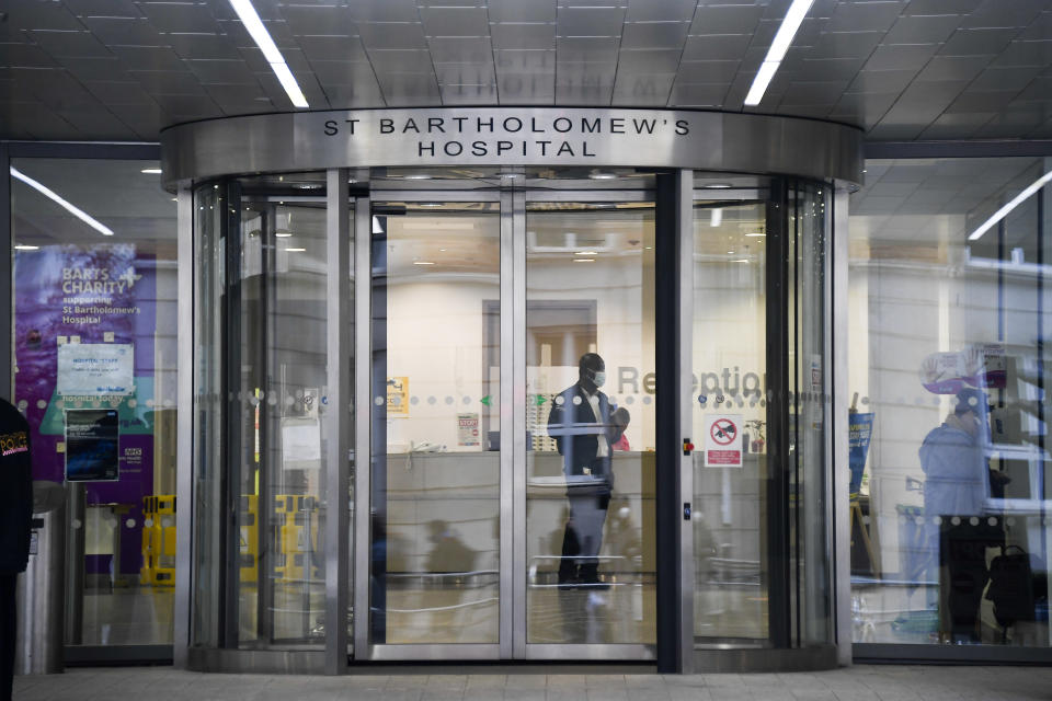 A member of staff wears a face mask as he stands inside the main entrance of St. Bartholomew's Hospital where Britain's Prince Philip is being treated, in London, Thursday, March 4, 2021. Buckingham Palace said Thursday that Prince Philip has undergone a successful procedure for a pre-existing heart condition, and will remain in hospital "for a number of days." (AP Photo/Alberto Pezzali)