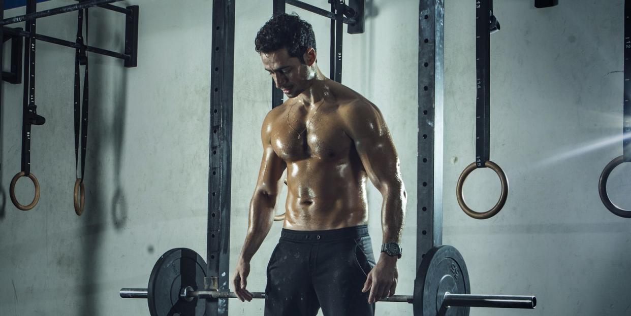 muscular built man preparing to lift barbell