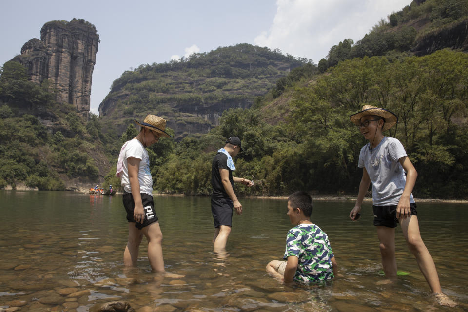 Tourists stand in shallow water along the Nine Bends River in Wuyishan in eastern China's Fujian province on Thursday, Aug. 15, 2019. (AP Photo/Ng Han Guan)