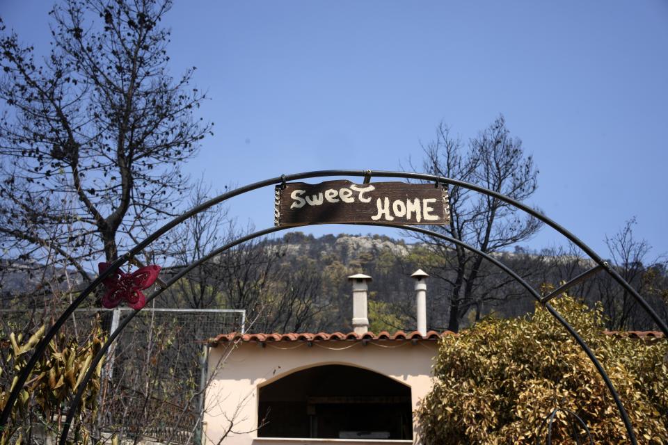 A sign stands in the burnt garden of a house in Acharnes suburb, on Mount Parnitha, in northwestern Athens, Greece, Thursday, Aug. 24, 2023. A major wildfire burning on the northwestern fringes of the Greek capital has torched homes and is now threatening the heart of a national park of Parnitha, one of the last green areas near the Greek capital. (AP Photo/Thanassis Stavrakis)