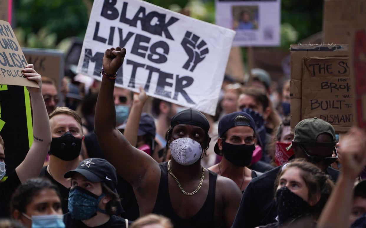 Protesters hold a "Black Lives Matter" sign and raise their fists as they march through Greenwich Village in a demonstration over the death of George Floyd - AFP