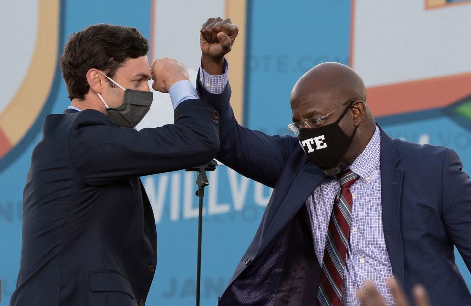 Democratic candidates for Senate Jon Ossoff (L) and Raphael Warnock (R) bump elbows on stage during a rally with US President-elect Joe Biden outside Center Parc Stadium in Atlanta, Georgia, on January 4, 2021. - President Donald Trump, still seeking ways to reverse his election defeat, and President-elect Joe Biden converge on Georgia on Monday for dueling rallies on the eve of runoff votes that will decide control of the US Senate. Trump, a day after the release of a bombshell recording in which he pressures Georgia officials to overturn his November 3 election loss in the southern state, is to hold a rally in the northwest city of Dalton in support of Republican incumbent senators Kelly Loeffler and David Perdue. Biden, who takes over the White House on January 20, is to campaign in Atlanta, the Georgia capital, for the Democratic challengers, Raphael Warnock and Jon Ossoff. (Photo by JIM WATSON / AFP) (Photo by JIM WATSON/AFP via Getty Images)