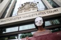 A demonstrator wearing a mask depicting Julian Assange protests outside of Westminster Magistrates Court, where a case hearing for U.S. extradition of Wikileaks founder Julian Assange is held, in London