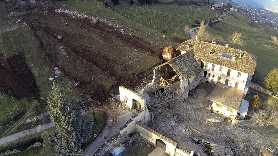 In this photo provided by Tareom.com Thursday, Jan. 30, 2014, and taken on Jan. 23, 2014, a huge boulder is seen after it stopped next to a farm house, while a second giant boulder, which detached during the same landslide on Jan. 21, 2014, whose trail can be seen on the left, missed the house by less than a meter, destroying the barn, and stopped in the vineyard below, in Ronchi di Termeno, in Northern Italy. According to reports, the Trebo family living there was unharmed in the landslide. (AP Photo/Markus Hell, Tareom.com, ho)