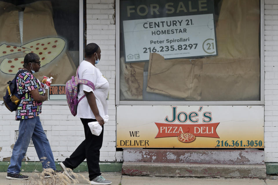 Two women walks past a closed down pizza deli, Thursday, June 4, 2020, in Cleveland. The state says more than 34,000 Ohioans filed unemployment claims during the last week of May. That is the lowest figure since Ohio's stay-at-home orders depressed the economy and led to widespread layoffs. The figure released Thursday by the Ohio Department of Job and Family Services is down from about 46,000 claims filed the previous week. (AP Photo/Tony Dejak)