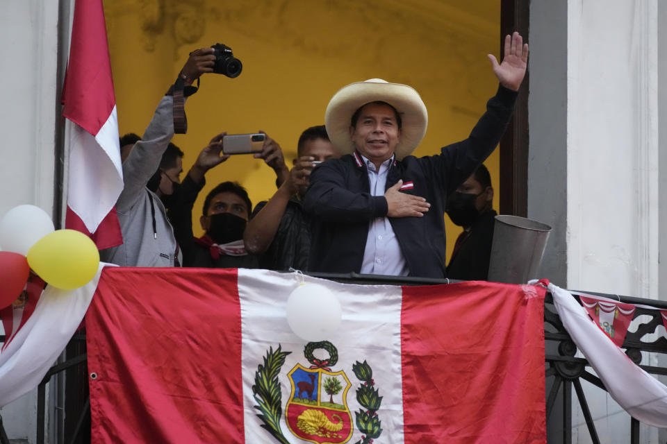 Presidential candidate Pedro Castillo waves to supporters celebrating partial election results that show him leading over Keiko Fujimori, at his campaign headquarters in Lima, Peru, Monday, June 7, 2021, the day after a runoff election. (AP Photo/Martin Mejia)