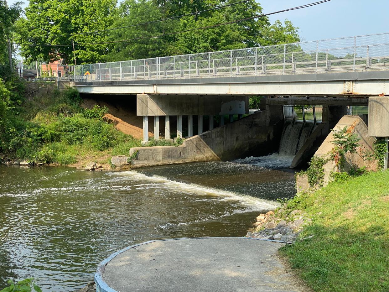 The south end of the Red Mill Pond dam in Tecumseh is pictured Thursday. The Lenawee County Drain Commissioner's Office is preparing a repair and realignment project for the dam's auxiliary spillway. Along with that project, the county has asked the Tecumseh City Council if it would fund a $161,000 project to create a proper kayak and canoe portage around the south end of the dam. The path carved by watercraft users between the pond and the River Raisin under the North Evans Street bridge can be seen on the left side of the photo.