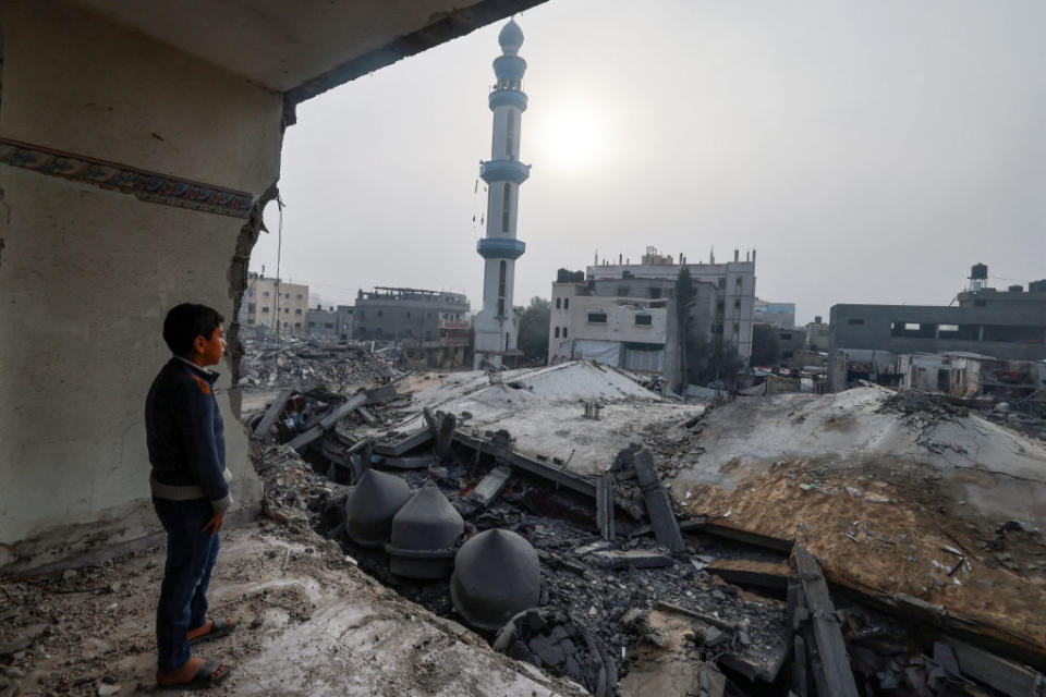 A child standing inside a damaged building, stares at the Al-Faruq mosque, levelled by Israeli bombardment in Rafah in the southern Gaza Strip on a foggy day on February 25, 2024, amid continuing battles between Israel and the Palestinian militant group Hamas. <span class="copyright">MOHAMMED ABED-AFP/ Getty Images</span>