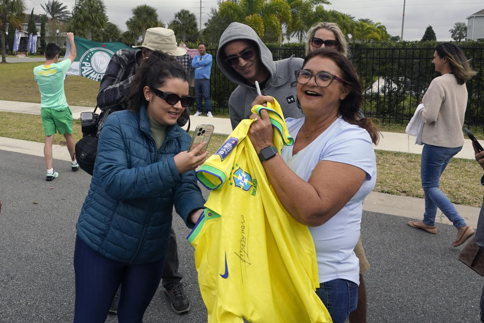Supporters of former Brazilian president Jair Bolsonaro show off items that Bolsonaro autographed at his residence Friday, Jan. 13, 2023, in Kissimmee, Fla. (AP Photo/John Raoux)