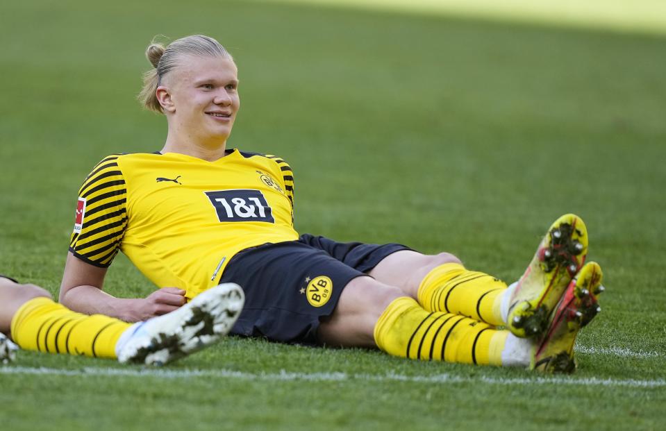 Dortmund's scorer Erling Haaland sits on the grass after winning the German Bundesliga soccer match between Borussia Dortmund and VfL Wolfsburg in Dortmund, Germany, Saturday, April 16, 2022. (AP Photo/Martin Meissner)