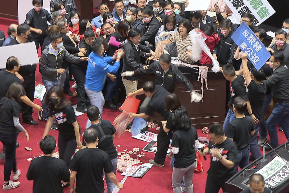 In this image made from video, lawmakers fight during a parliament session in Taipei, Taiwan, Friday, Nov. 27, 2020. Taiwan's lawmakers got into a fist fight and threw pig guts at each other Friday over a soon-to-be enacted policy that would allow imports of U.S. pork and beef. A blue banner at right reads: “Protest against ractopamine pork, We want a referendum.” (FTV via AP)