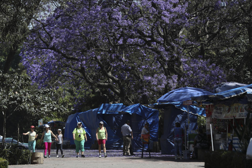 Tourists walk past the closed stalls outside of the Anthropology Museum in Mexico City, Tuesday, March 24, 2020. Beginning Monday, Mexico's capital shut down museums, bars, gyms, churches, theaters, and other non-essential businesses that gather large numbers of people, in an attempt to slow the spread of the new coronavirus. (AP Photo/Fernando Llano)