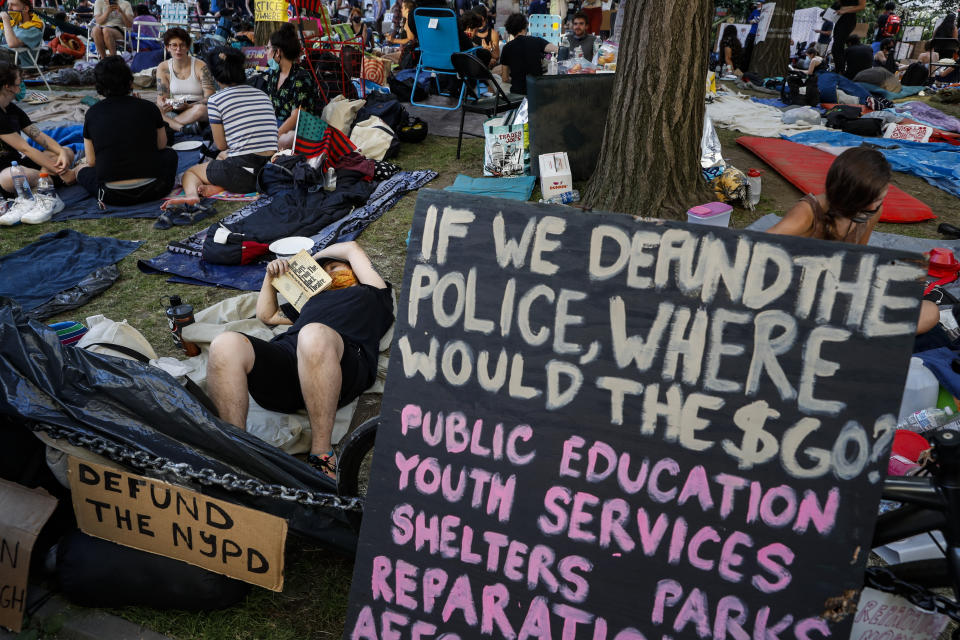 Protesters occupy an encampment outside City Hall beside signs calling for the defunding of police, Friday, June 26, 2020, in New York. (AP Photo/John Minchillo)