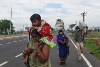 Migrant workers and their family members walk with their belongings on a highway towards Uttar Pradesh as they leave for their villages during a government-imposed nationwide lockdown as a preventive measure against the COVID-19 coronavirus, in Faridabad on March 27, 2020. (Photo by Money SHARMA / AFP) (Photo by MONEY SHARMA/AFP via Getty Images)