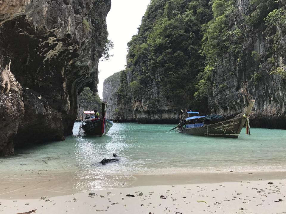 In this Dec. 5, 2016 photo, long-tail boats sit near a small beach on Ko Phi Phi Leh, an island off the southwestern coast of Thailand. The smaller of the Phi Phi Islands is a tourist hotspot for its beautiful water, party atmosphere and famed Maya Bay, where the movie "The Beach" was filmed. (AP Photo/Courtney Bonnell)